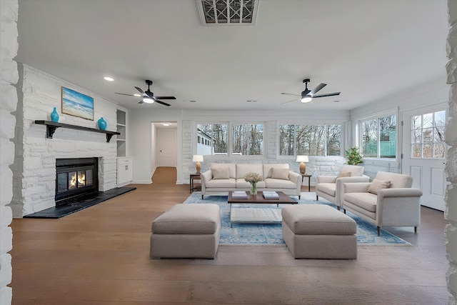 living room with hardwood / wood-style flooring, a fireplace, built in features, and ceiling fan