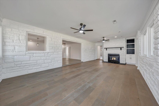 unfurnished living room with dark hardwood / wood-style flooring, a stone fireplace, and ceiling fan