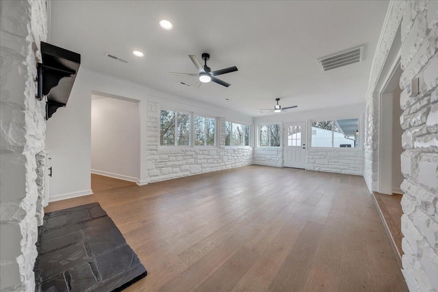 unfurnished living room with ceiling fan, brick wall, and hardwood / wood-style floors