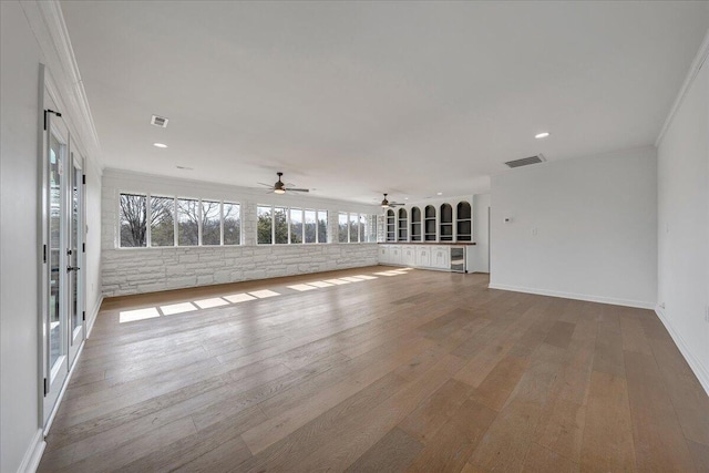 unfurnished living room with crown molding, ceiling fan, brick wall, and light hardwood / wood-style flooring