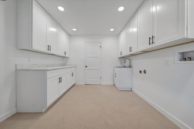 laundry room featuring light carpet, washer hookup, sink, and cabinets