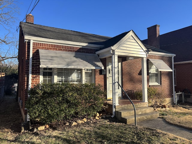 view of front of property with a chimney and brick siding