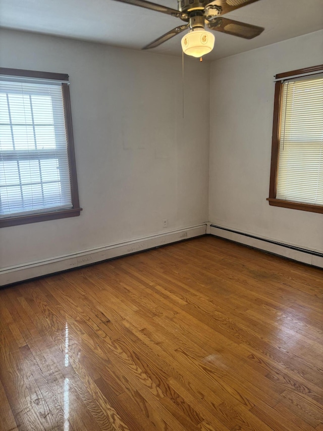 spare room featuring a baseboard heating unit, wood finished floors, and a ceiling fan