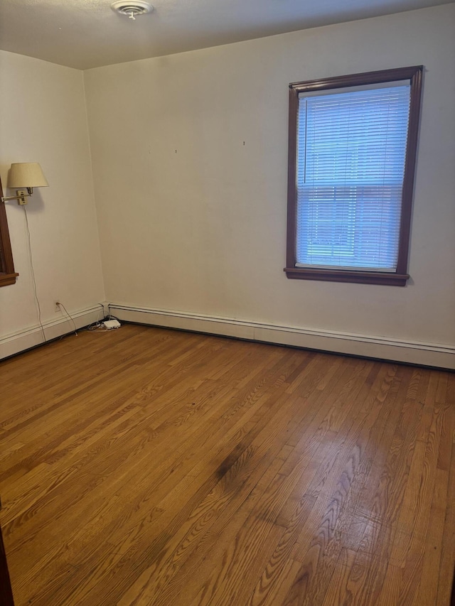 empty room featuring baseboard heating and wood finished floors