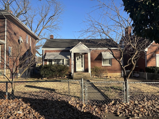 view of front of property with a fenced front yard, a chimney, a gate, and brick siding