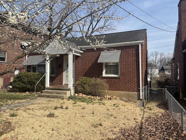 bungalow-style home with a gate, brick siding, and fence