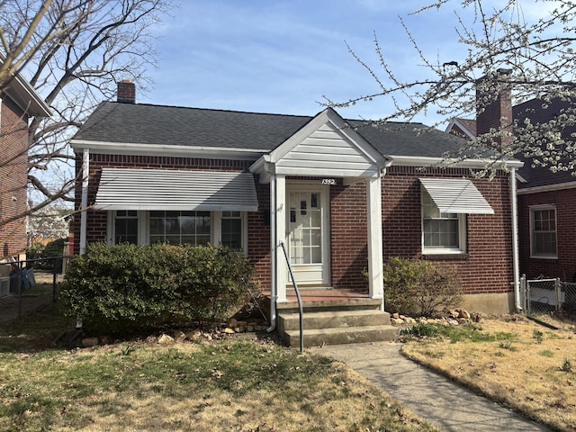 bungalow-style house with brick siding, roof with shingles, a chimney, and fence