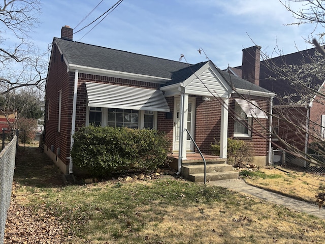 bungalow with brick siding, a shingled roof, a chimney, and fence