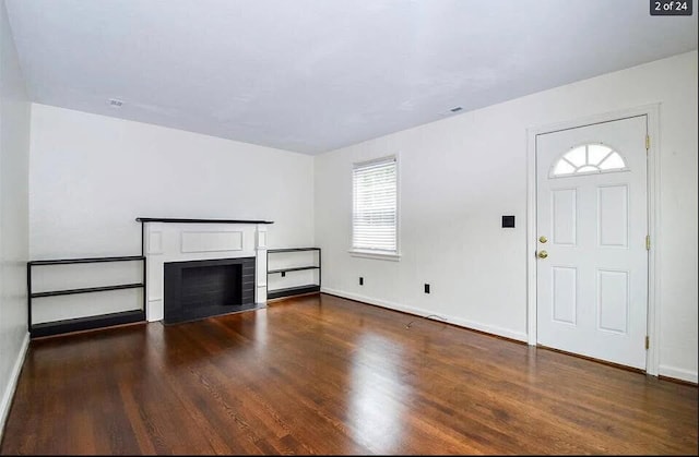 unfurnished living room featuring a fireplace and dark wood-type flooring