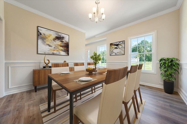 dining space with crown molding, hardwood / wood-style flooring, and an inviting chandelier