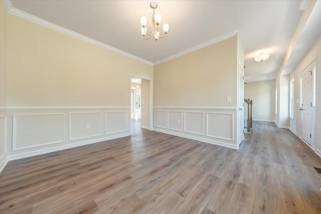 empty room with an inviting chandelier, crown molding, and light hardwood / wood-style flooring