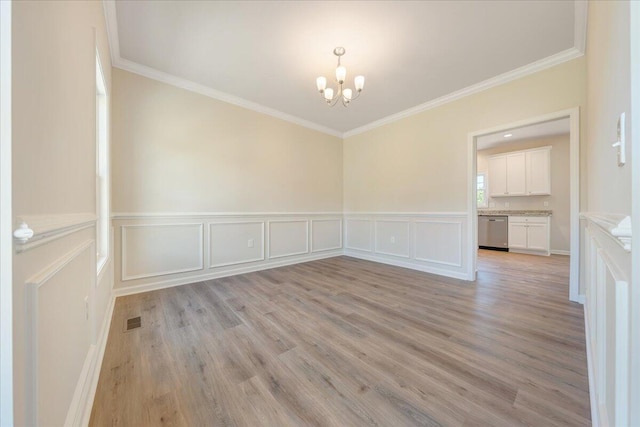 spare room with light hardwood / wood-style flooring, a chandelier, and ornamental molding