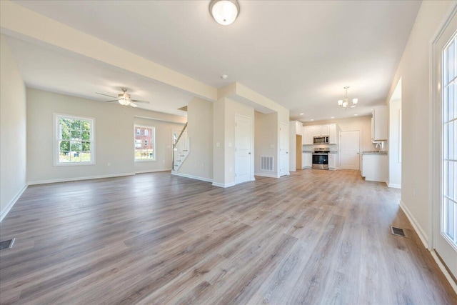 unfurnished living room featuring ceiling fan with notable chandelier, light hardwood / wood-style flooring, and sink