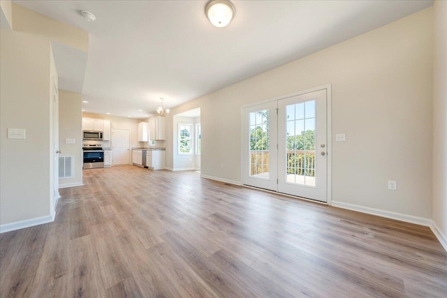 unfurnished living room with light hardwood / wood-style floors and a notable chandelier