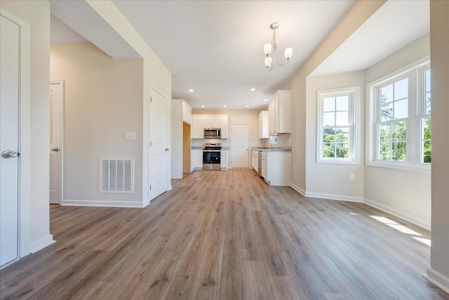 unfurnished living room featuring light hardwood / wood-style floors and an inviting chandelier