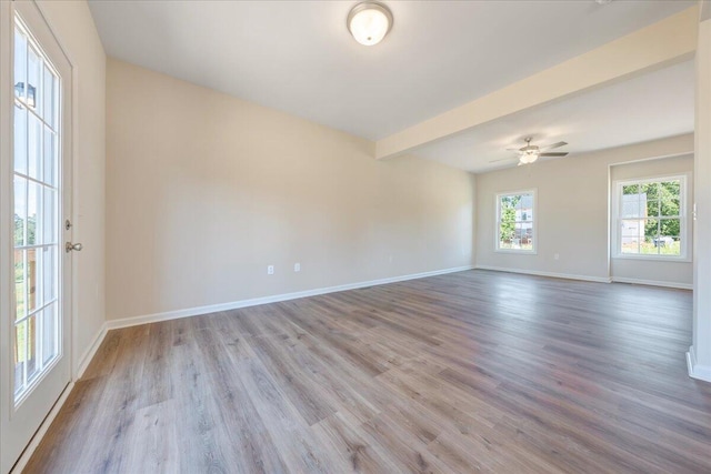 unfurnished room featuring beam ceiling, light wood-type flooring, and ceiling fan