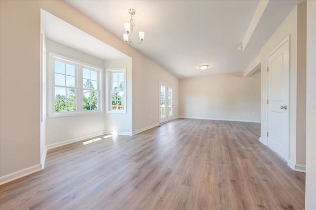 unfurnished room featuring an inviting chandelier and light hardwood / wood-style flooring