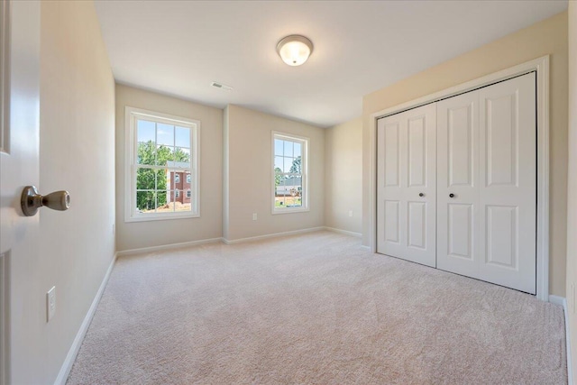 unfurnished bedroom featuring light carpet and a closet