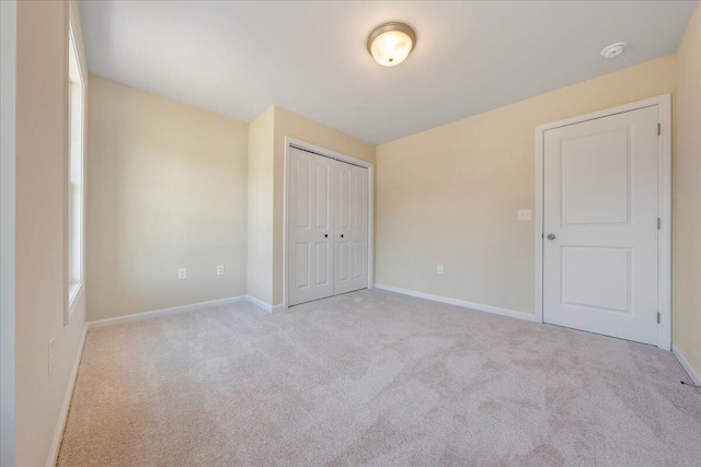 unfurnished bedroom featuring light carpet and a closet