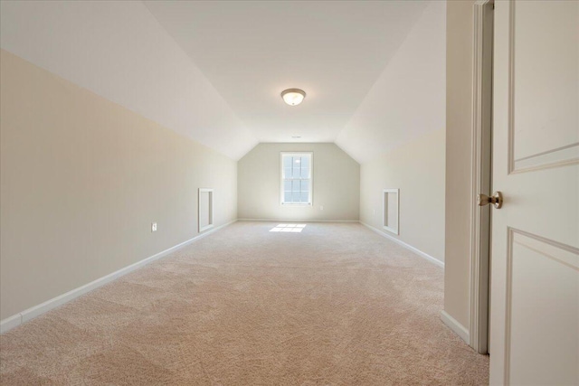 additional living space featuring light carpet and vaulted ceiling