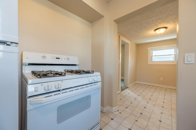 kitchen with a textured ceiling, white gas range, and white cabinets