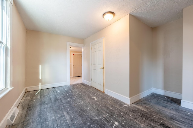 spare room featuring a textured ceiling and dark hardwood / wood-style flooring