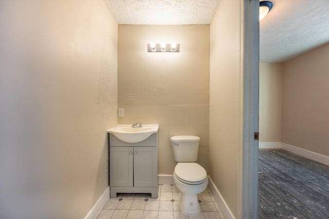 bathroom featuring toilet, vanity, tile patterned floors, and a textured ceiling