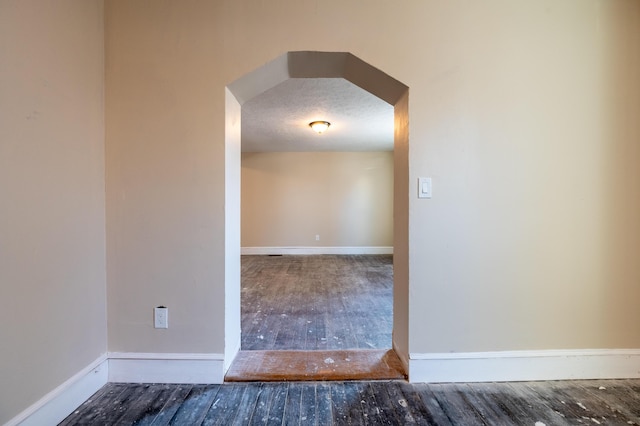 spare room with a textured ceiling and dark hardwood / wood-style flooring