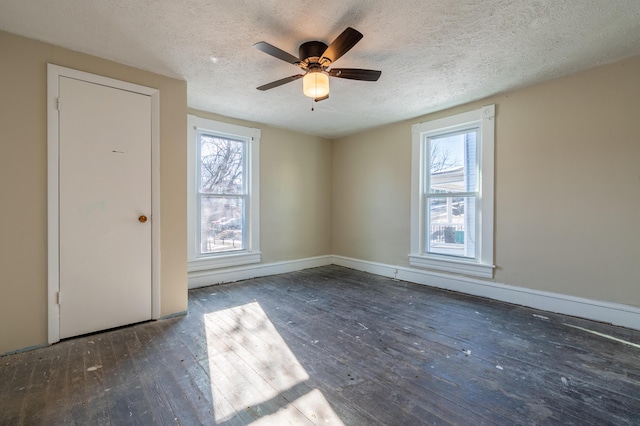 spare room featuring a textured ceiling, dark hardwood / wood-style flooring, and a healthy amount of sunlight