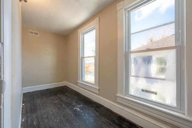 spare room with a textured ceiling and dark hardwood / wood-style flooring