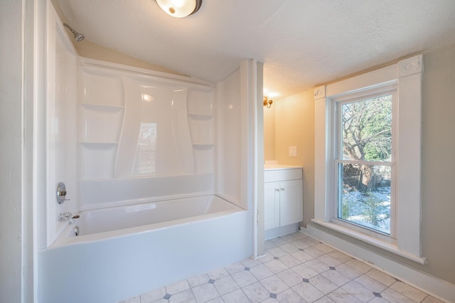 bathroom with tub / shower combination, a textured ceiling, vanity, and lofted ceiling