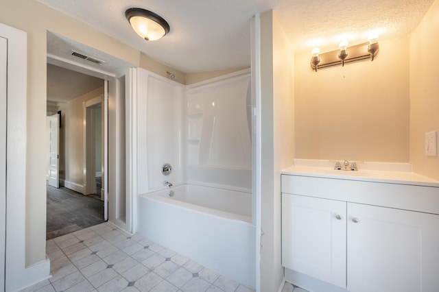 bathroom with a textured ceiling, shower / bathtub combination, and vanity