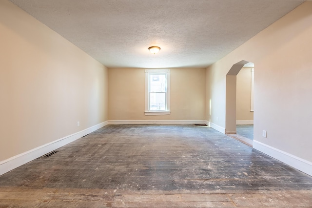 unfurnished room with dark hardwood / wood-style flooring and a textured ceiling