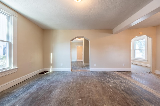 unfurnished room featuring a healthy amount of sunlight, dark hardwood / wood-style floors, and a textured ceiling