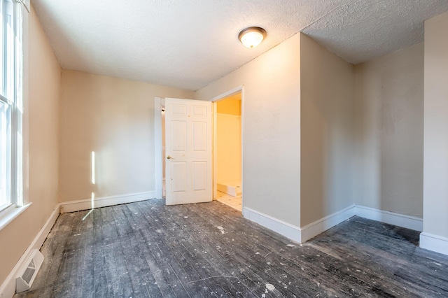 empty room with a textured ceiling and dark hardwood / wood-style floors