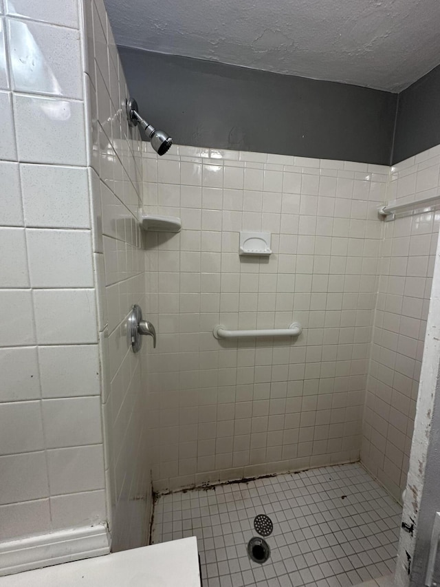 bathroom featuring a tile shower and a textured ceiling