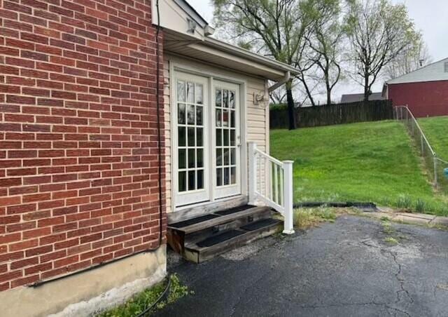 property entrance featuring french doors, a patio, and a lawn