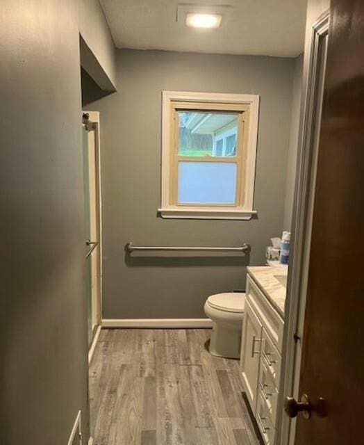 bathroom featuring hardwood / wood-style floors, vanity, an enclosed shower, and toilet