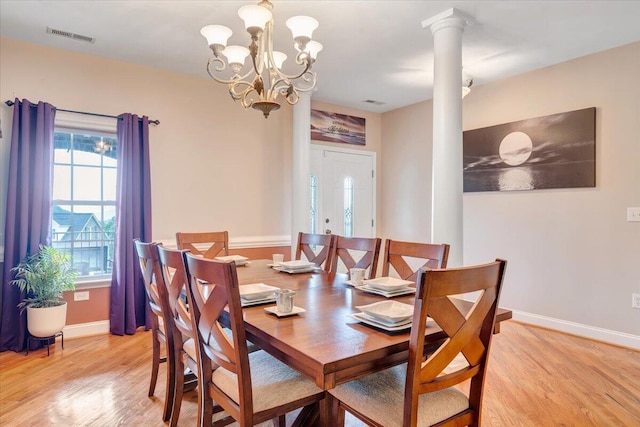 dining space with decorative columns, a notable chandelier, and light hardwood / wood-style flooring