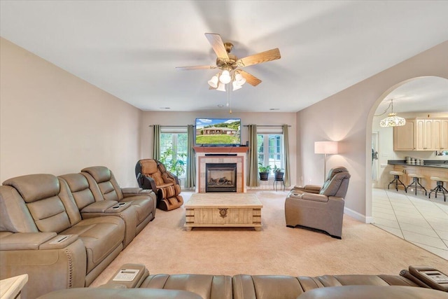 living room featuring ceiling fan, light colored carpet, and a tile fireplace