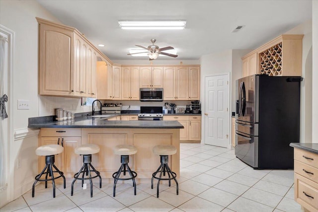 kitchen featuring kitchen peninsula, stainless steel appliances, ceiling fan, a breakfast bar area, and light tile patterned flooring