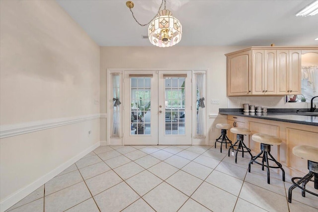 kitchen featuring pendant lighting, a notable chandelier, french doors, a kitchen bar, and light brown cabinets