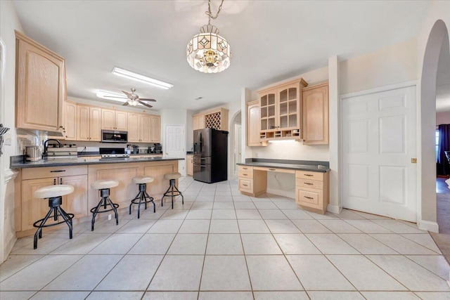 kitchen with a breakfast bar area, appliances with stainless steel finishes, hanging light fixtures, kitchen peninsula, and ceiling fan with notable chandelier