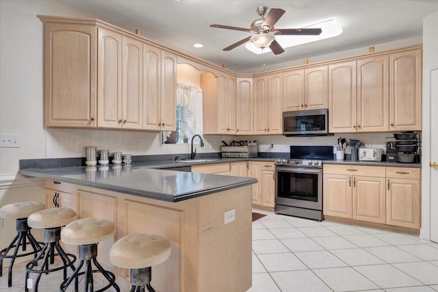 kitchen featuring appliances with stainless steel finishes, kitchen peninsula, a breakfast bar area, and sink