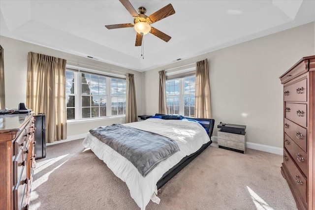 carpeted bedroom featuring ceiling fan and a tray ceiling