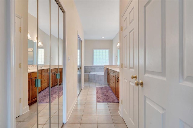 bathroom with tiled bath, tile patterned flooring, and vanity