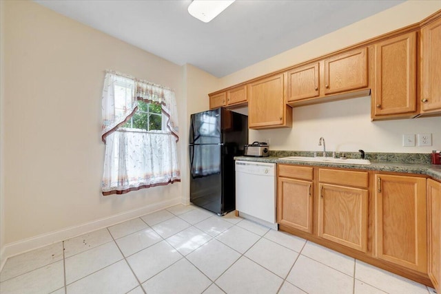 kitchen with black fridge, light tile patterned floors, sink, and dishwasher