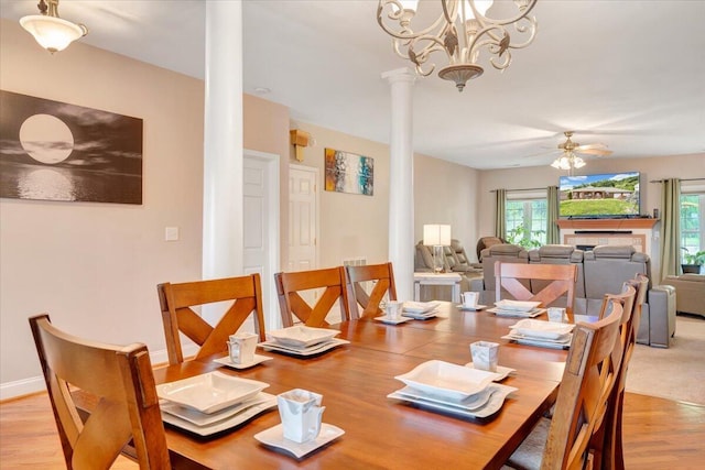 dining area featuring ceiling fan with notable chandelier, decorative columns, and light hardwood / wood-style flooring