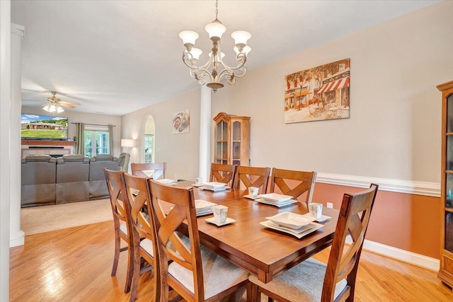 dining room with ceiling fan with notable chandelier and light wood-type flooring