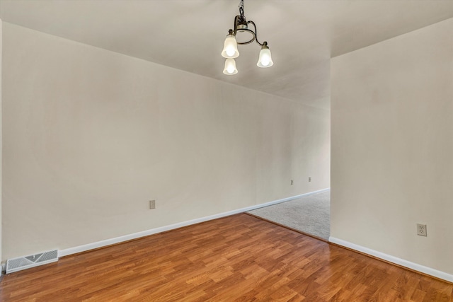 spare room featuring hardwood / wood-style floors and a notable chandelier